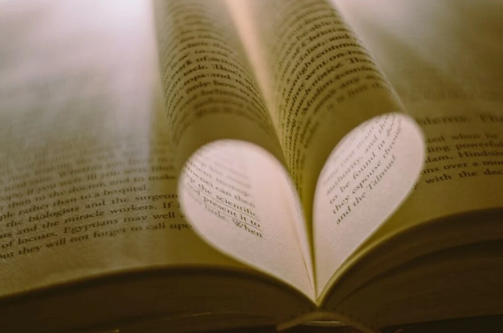 Photo de pages d'un livre en forme d'un cœur avec de la lumière.