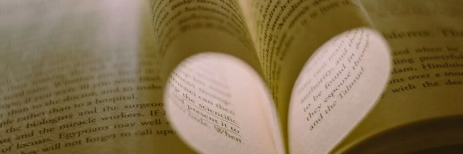 Photo of pages of a book in the shape of a heart with light.